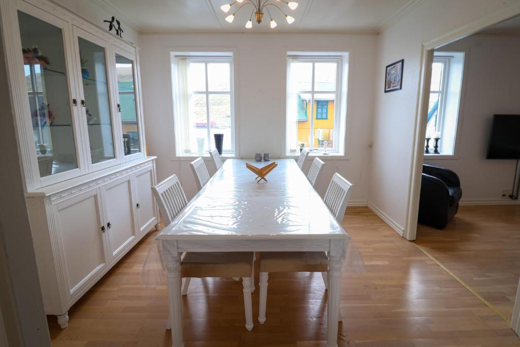 a dining room with a white table and chairs at Spacious 3-Bedroom Apartment with Comfy Beds in Central Vágur, Island of Suðuroy in Vágur