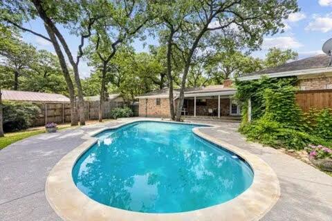 a large blue swimming pool in front of a house at 4-Bedroom Home with Private Pool in Euless in Euless