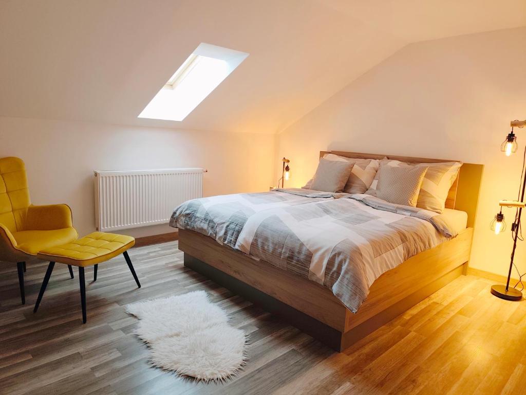 a bedroom with a bed and a yellow chair at Apartmán Altis in Tatranska Strba