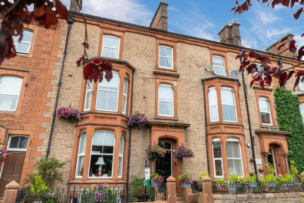 an old brick building with windows and flowers at Glendale Guest House in Penrith