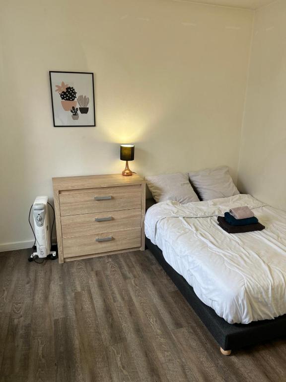 a bedroom with a bed and a dresser with a lamp at Private Room in a Shared Appartment in Asnières-sur-Seine