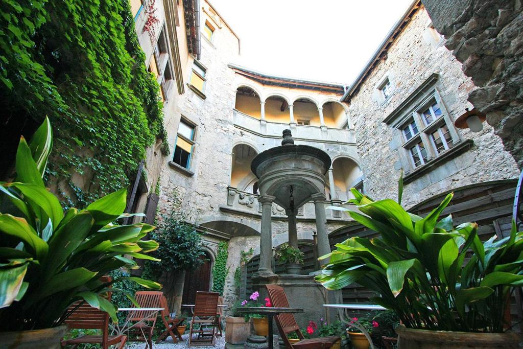 a building with a courtyard with plants and a water fountain at Hôtel Restaurant d'Alibert in Caunes-Minervois