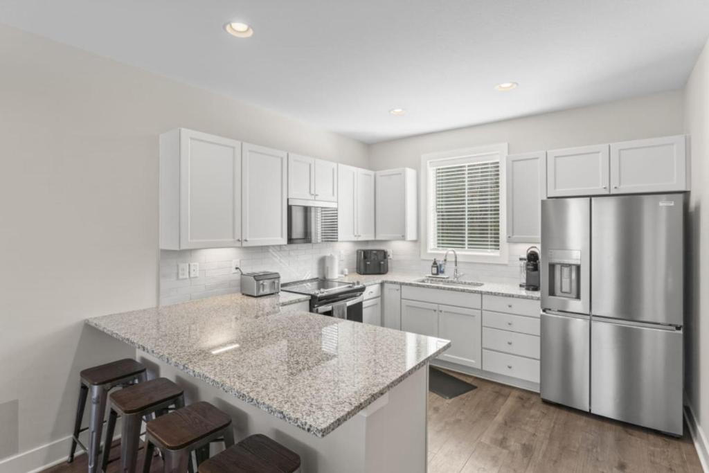 a kitchen with white cabinets and a stainless steel refrigerator at Riverview Retreat: Neyland Stadium – sleeps 8! in Knoxville