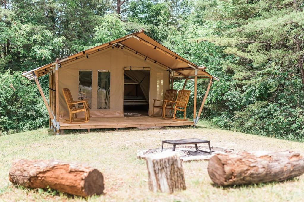 a tent with chairs and a table in a field at GlampKnox Canvas Campground - Grande in Knoxville
