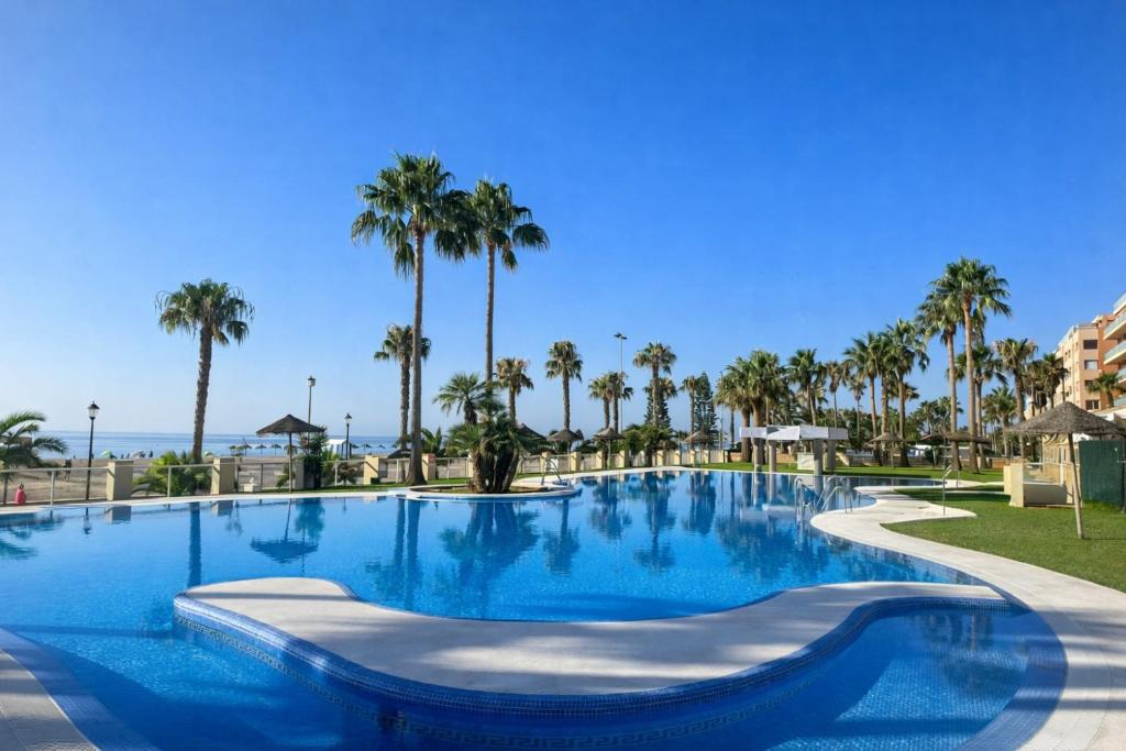 a swimming pool at a resort with palm trees at Apartamento Olimpic Beach in Roquetas de Mar