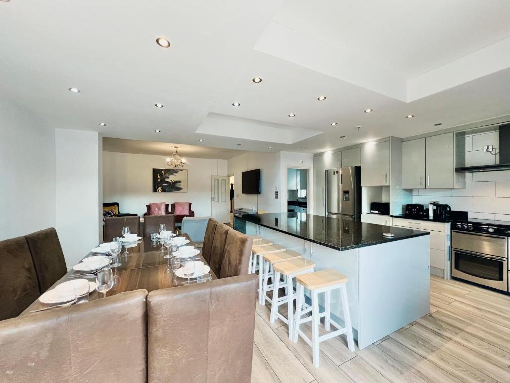 a kitchen with a long dining table and a kitchen with a counter at Gants Hill House in Redbridge