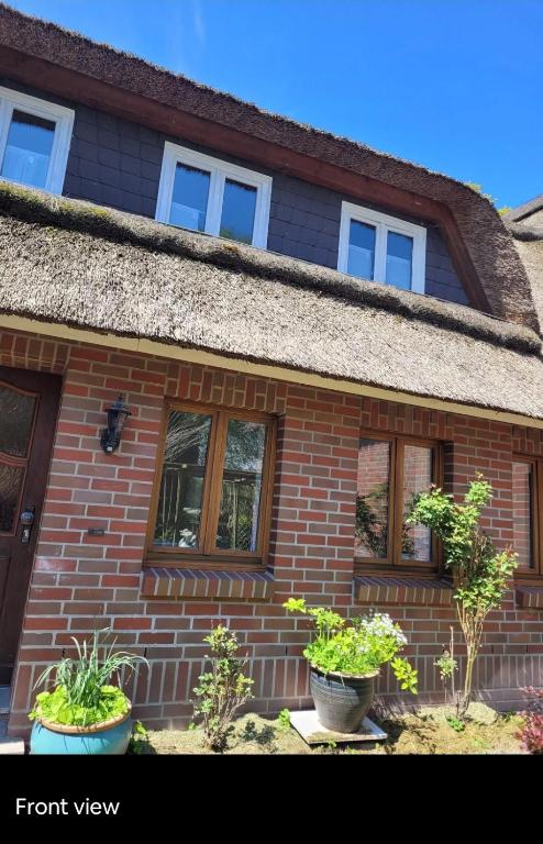 a brick house with two potted plants in front of it at Oakwoods in Holste