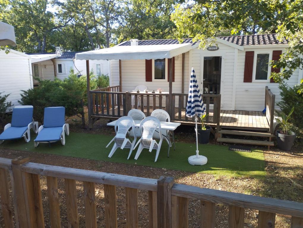a yard with a table and chairs and an umbrella at Mobil home YANN in Sainte-Croix-de-Verdon