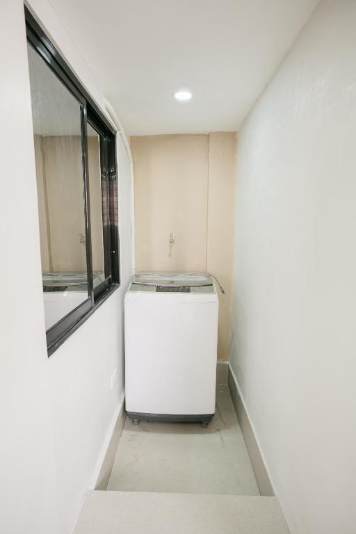 a small white refrigerator in a room with a window at Joanna Transient Home in Palestina