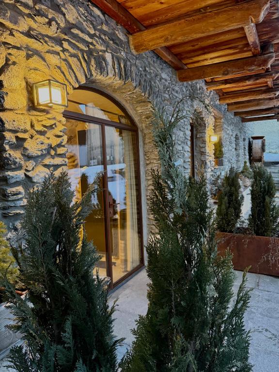two christmas trees in front of a stone building at Granuit Alpine Home in Sauze di Cesana