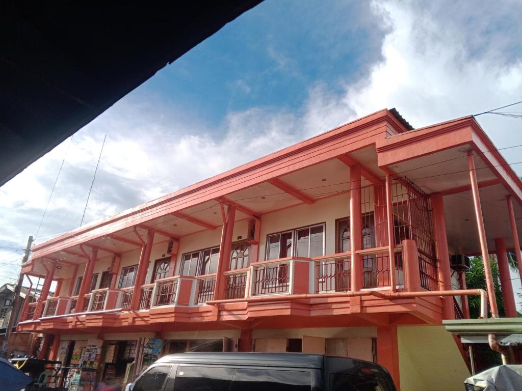 a red building with a balcony on a street at Felipenas Lodging House in Matalom