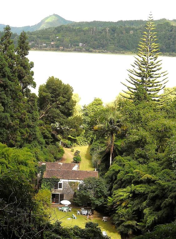 a house in the middle of a forest with a lake at Casa da Cascata in Furnas