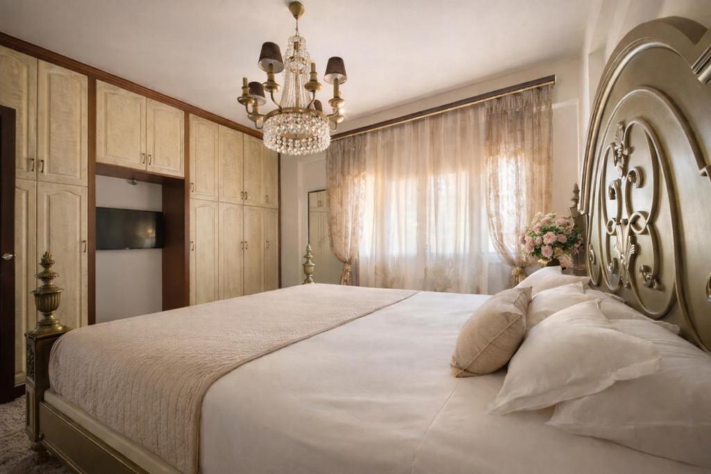 a bedroom with a large white bed with a chandelier at Royal stylish view apartment in Koropi