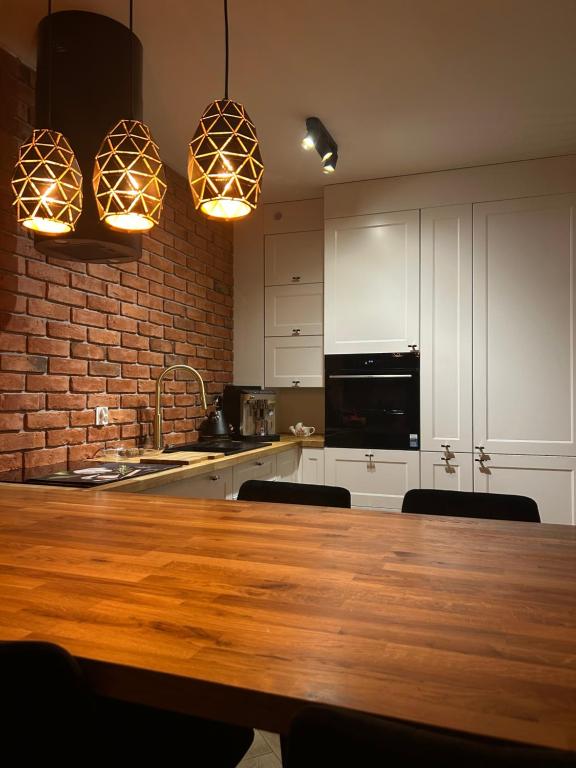 a kitchen with a wooden table and two pendant lights at Apartament Bond in Szczawno-Zdrój