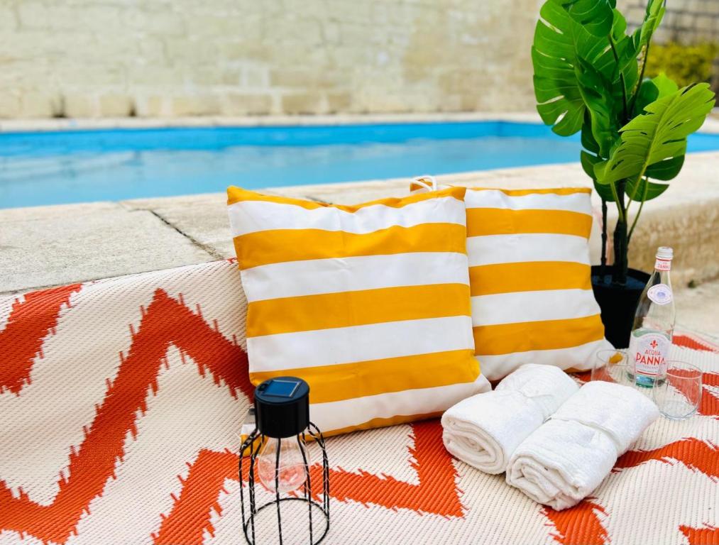 a picnic table with towels and pillows next to a pool at Panoramic Ocean View Villa in Is-Swieqi