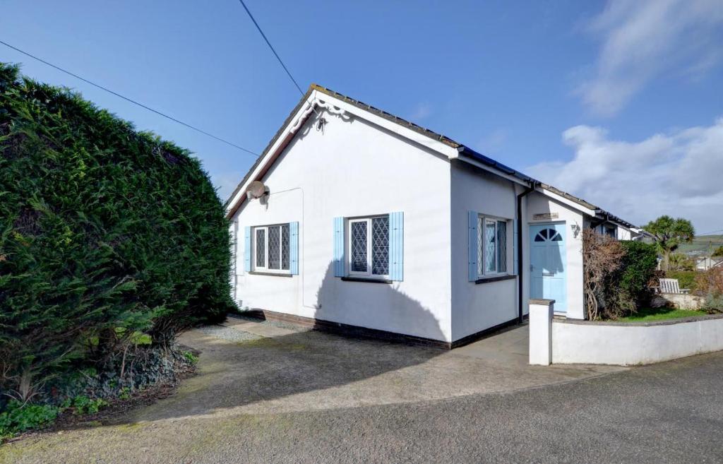 a white house with a large bush next to it at 2 Bed in Croyde oc-sandc in Croyde
