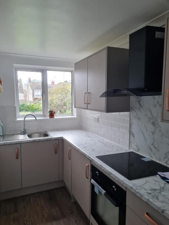 a kitchen with white cabinets and a sink and a window at 1 Bedroom Flat Ground Floor - Central Dunstable in Dunstable
