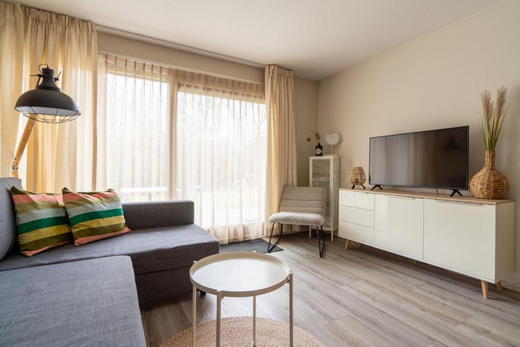 a living room with a couch and a flat screen tv at Appartement De Jutter, Resort Amelander Kaap in Hollum