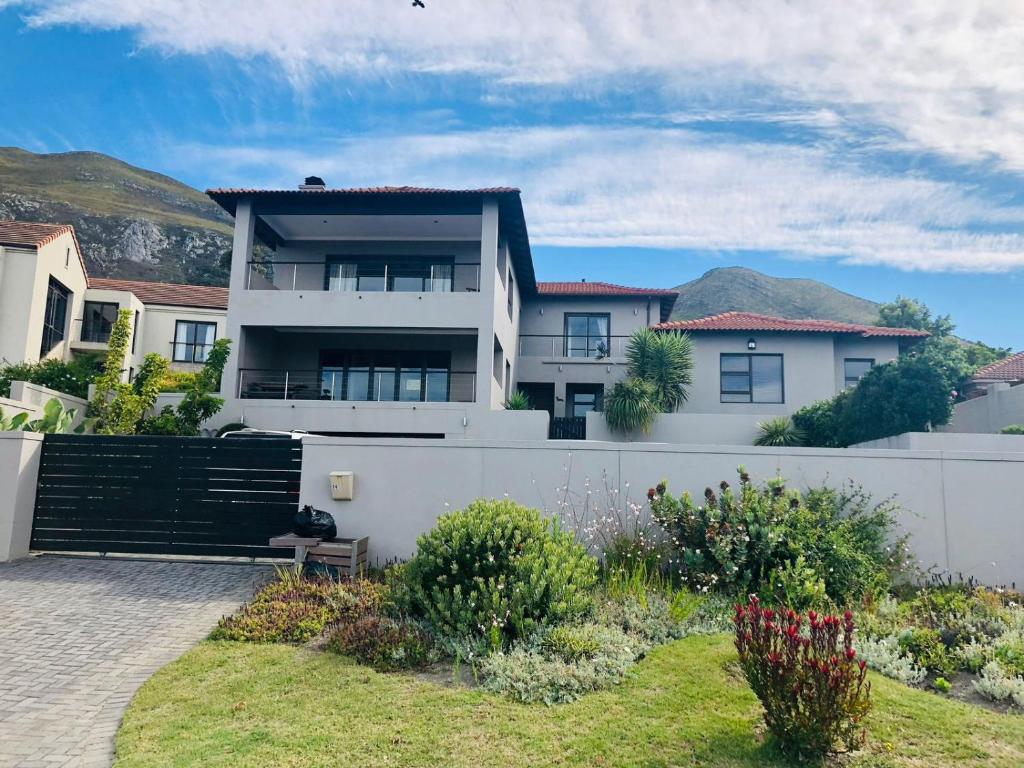 a white house with a fence and a yard at Chasing Jacuzzi Sunsets sea and mountain views in Hermanus