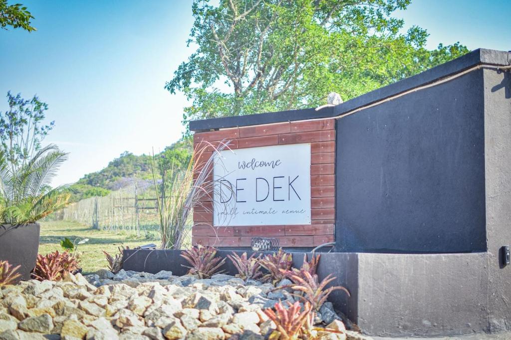 a sign on a brick wall in a garden at De Dek Venue & Accommodation in Guthrie