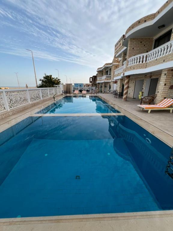 a swimming pool with blue water in front of a building at Soltan palace in Qaryat Wādī ‘Abbādī 1