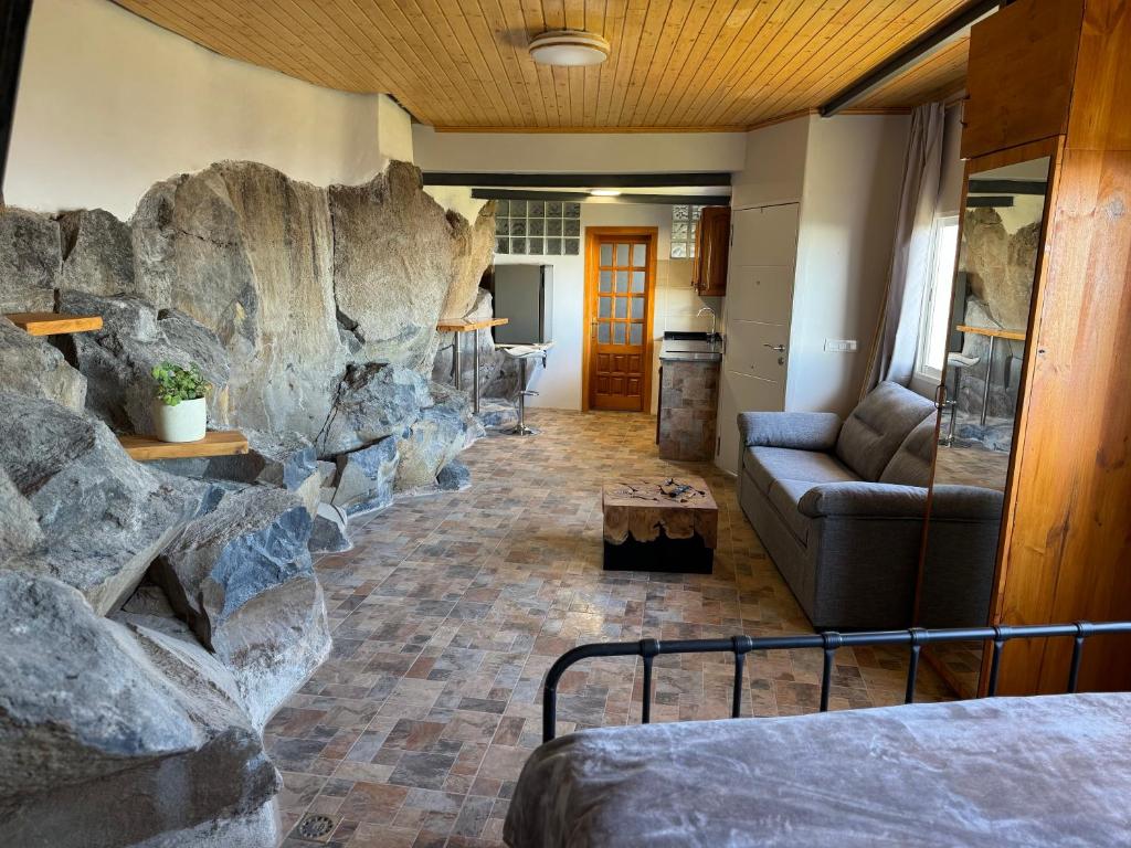a room with a rock wall and a bed and a couch at Casa Roca in Arona