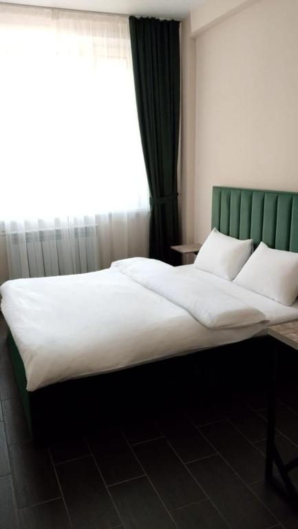 a large bed in a room with a window at Berloga Hotel in Pavlodar