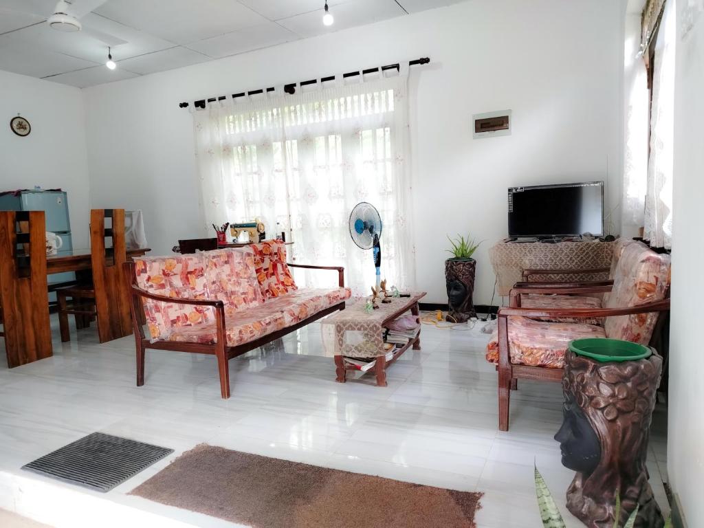 a living room with a couch and chairs and a tv at Vinal Inn Midigama in Midigama East