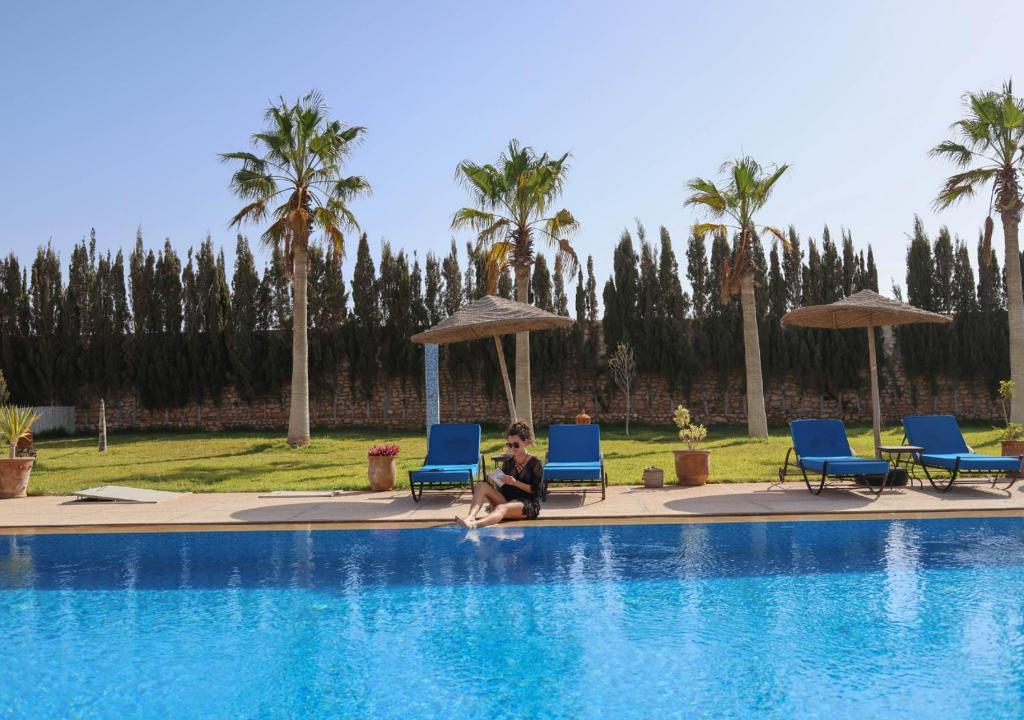 a woman sitting on the edge of a swimming pool at Dar Ayman Essaouira in Essaouira