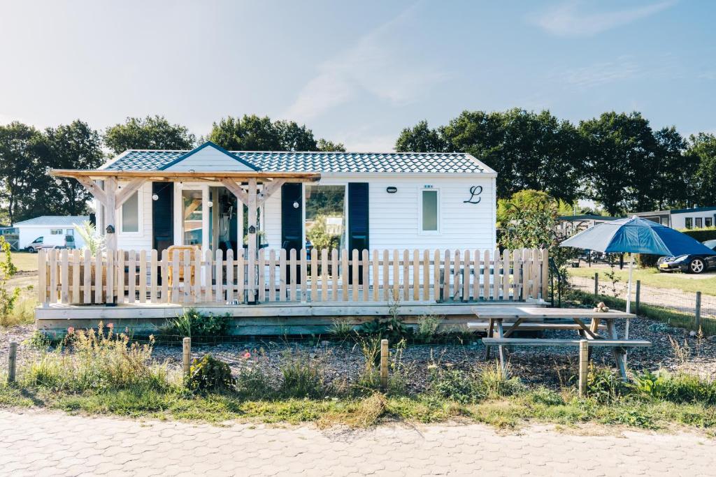 a small white house with a picnic table and an umbrella at Louisiana in Anloo