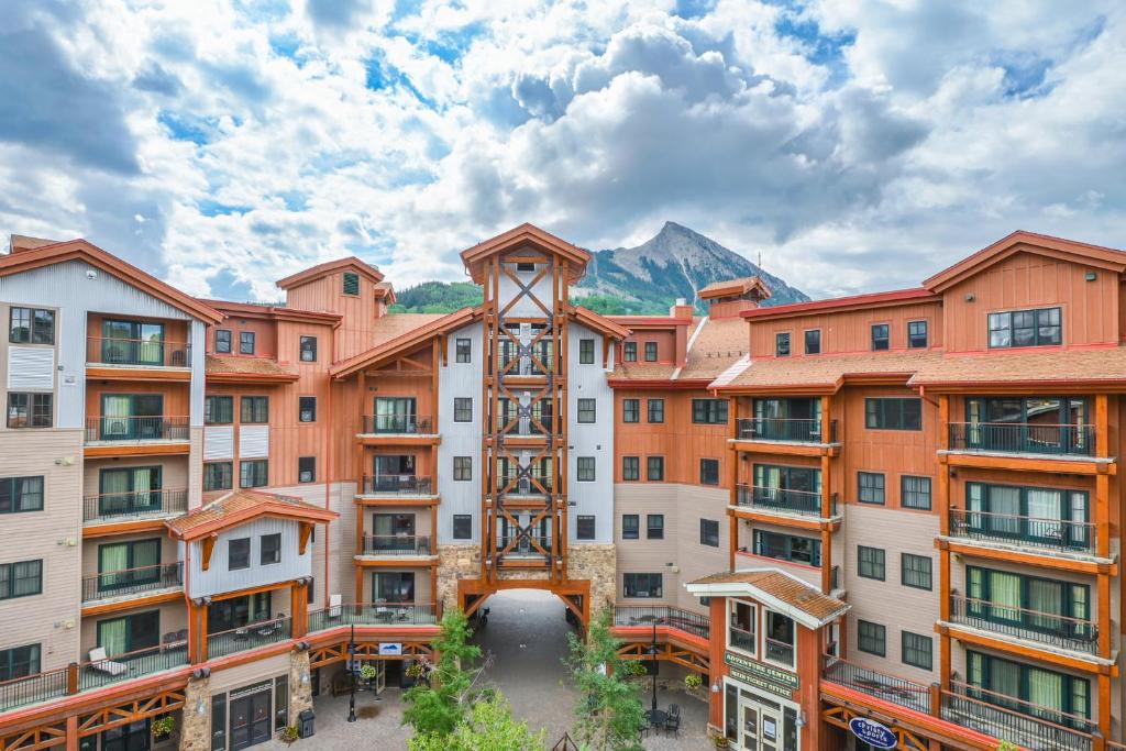 an apartment building with a mountain in the background at The Lodge at Mountaineer Square, A Vail Resorts Property in Mount Crested Butte