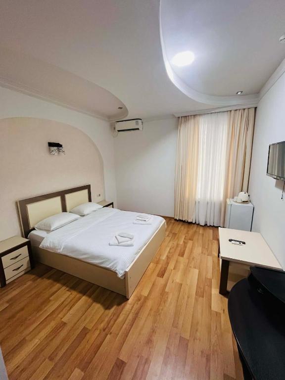 a bedroom with a large bed and wooden floors at Lux Palace Hotel in Kutaisi