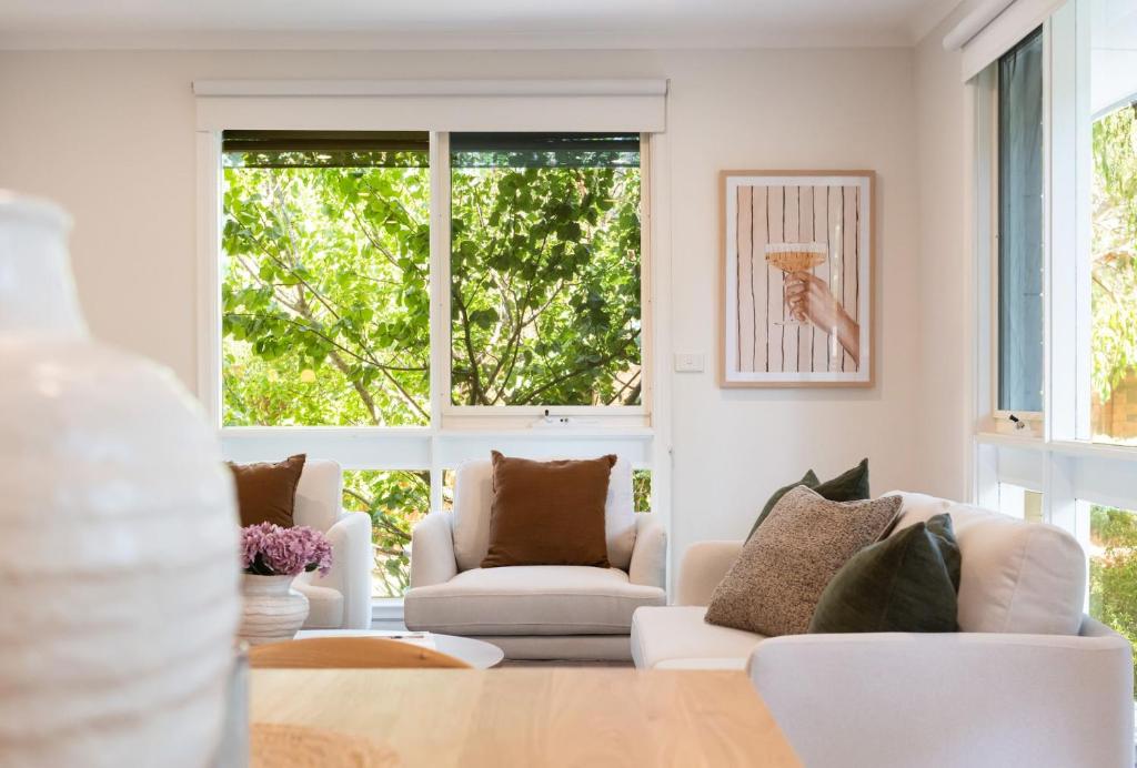 a living room with white furniture and large windows at Sundance steps to Half Moon Bay in Black Rock North