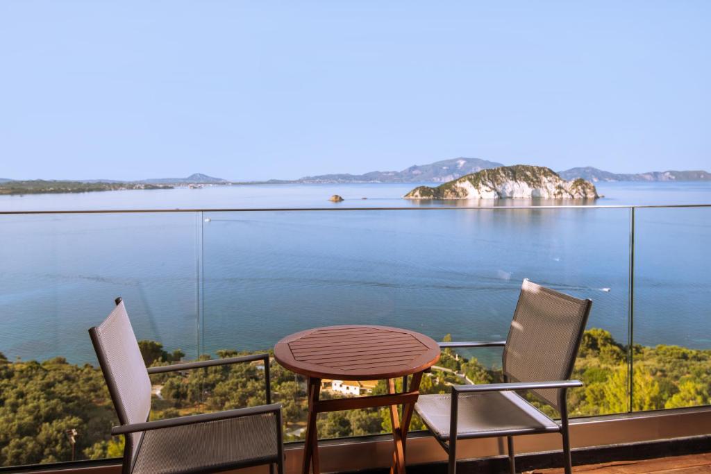 a table and chairs on a balcony overlooking the water at Bay View Suites & Apartments in Marathias