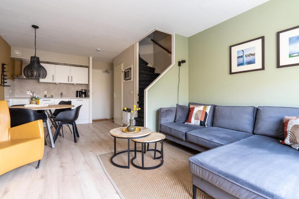 a living room with a blue couch and a table at Appartement De Bosrand, Resort Amelander Kaap in Hollum