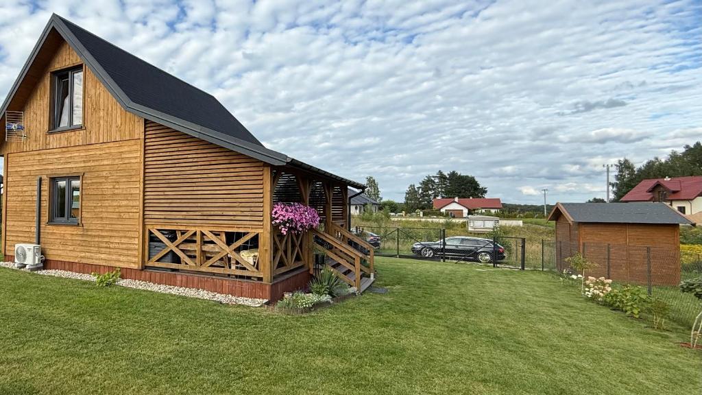 a wooden cabin with a black roof on a yard at Cud Miód Mazury in Bogaczewo