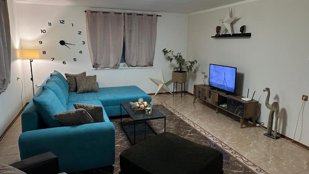 a living room with a blue couch and a tv at Apartman Staro Petrovo Selo in Staro Petrovo Selo