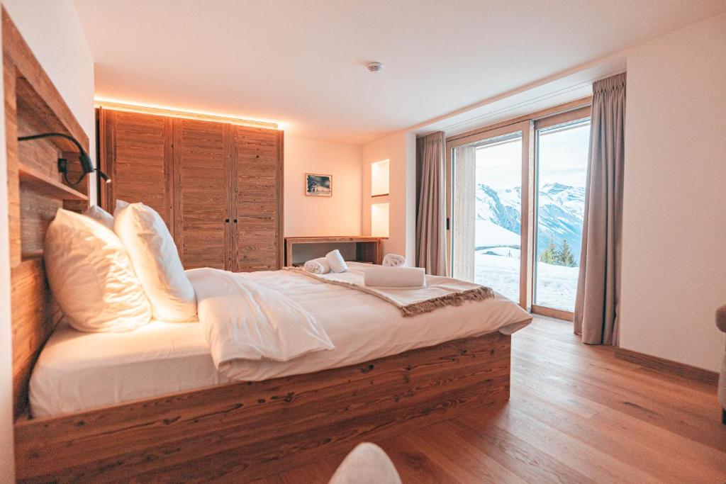 a bedroom with a large bed and a large window at Nînda Boutique Hôtel in Nendaz