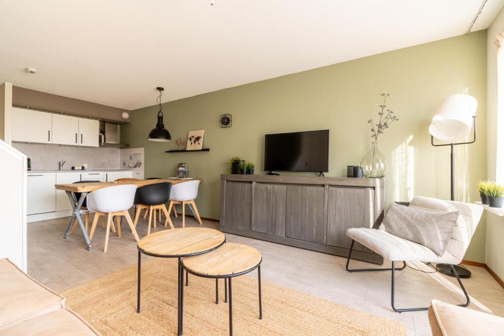 a kitchen and living room with a table and chairs at Appartement Senang, Resort Amelander Kaap in Hollum