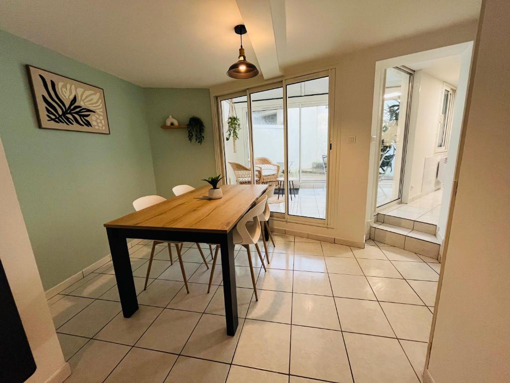 a dining room with a wooden table and chairs at Le Liseo - Terrasse, véranda au cœur du centre ville in Niort