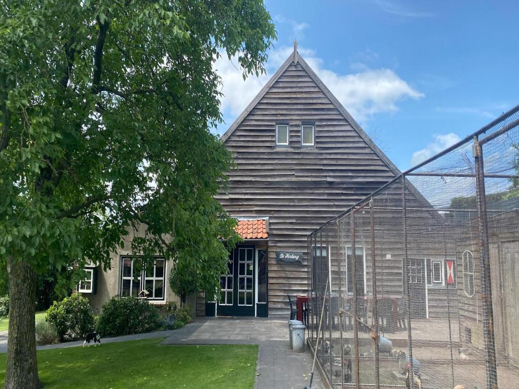 a large wooden house with a gambrel roof at Farmhouse in Nieuwleusen near Lake and Nature in Bergen op Zoom