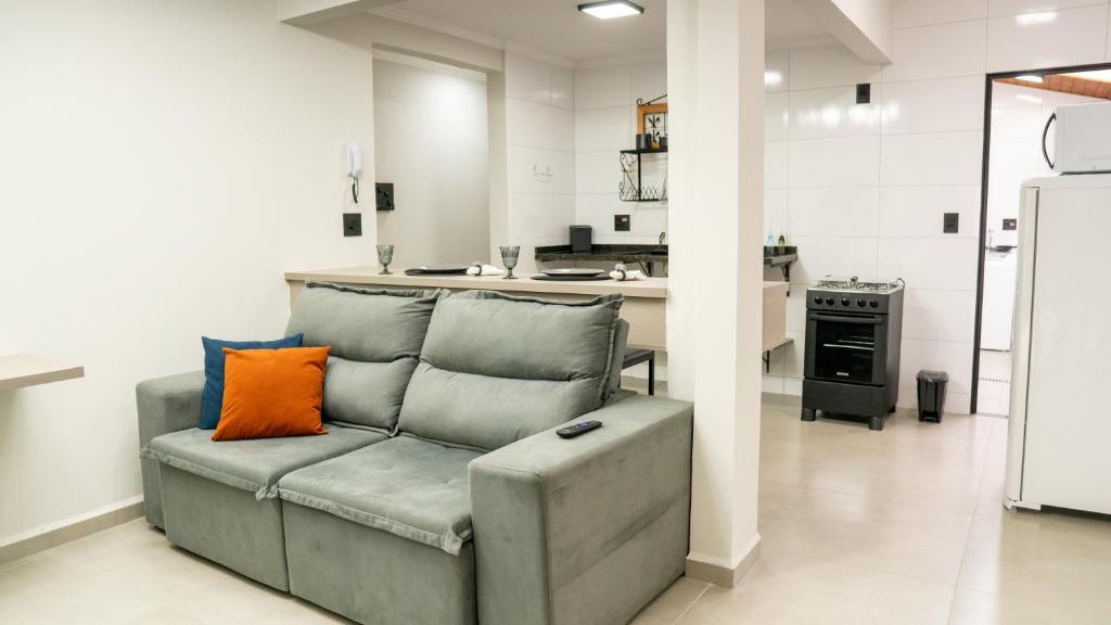 a living room with a couch with an orange pillow at Jahu Center Casas Un 4 in Jaú