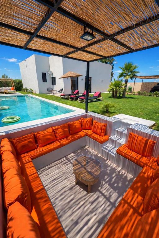 a pool with a couch and chairs next to a swimming pool at Villa soléa - Route Ouarzazate in Marrakesh