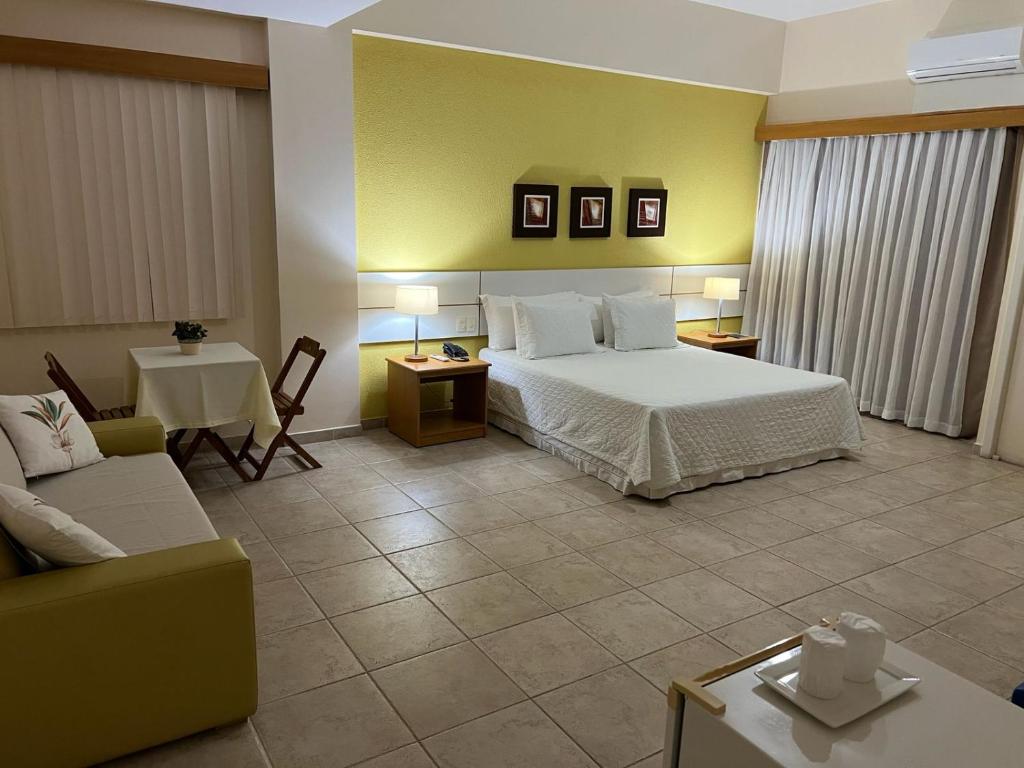 a bedroom with a bed and a couch and a table at Pousada Barlavento in Iriri