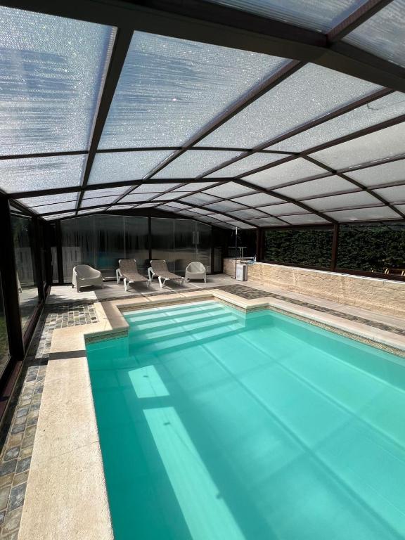 a large swimming pool with a roof with chairs at VILLA TOMILLARES in Los Tomillares