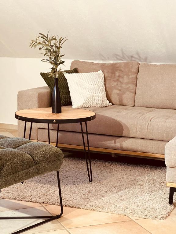 a living room with a couch and a table with a vase on it at Groasmückle Apartment in Tauberbischofsheim