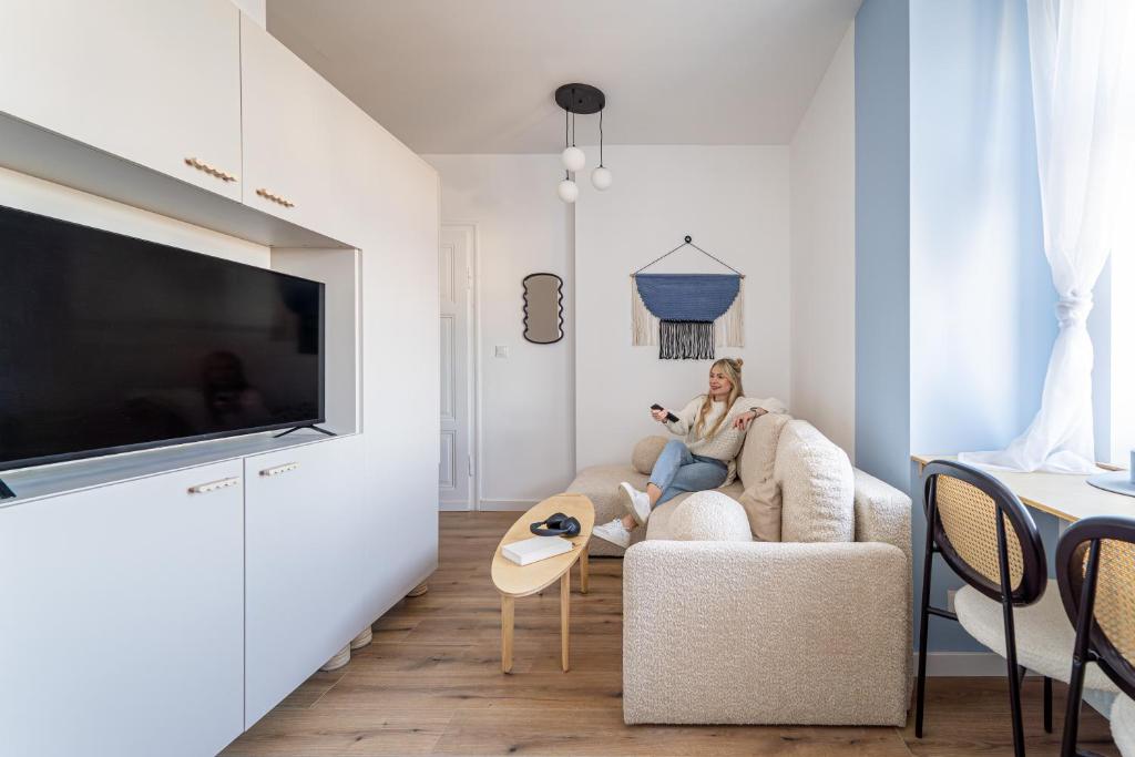 a woman sitting on a couch in a living room at Cloud Comfort Studio Willa Miejska Górka in Miejska Górka