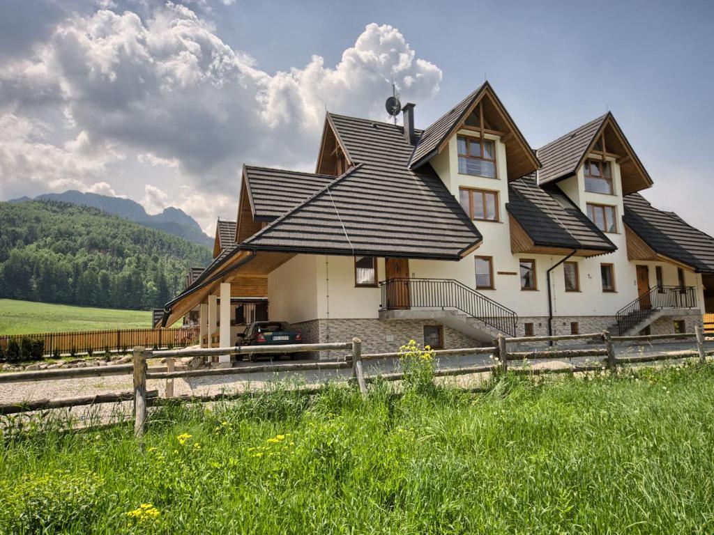 a house with a gambrel roof on a field at Willa Mnich in Zakopane