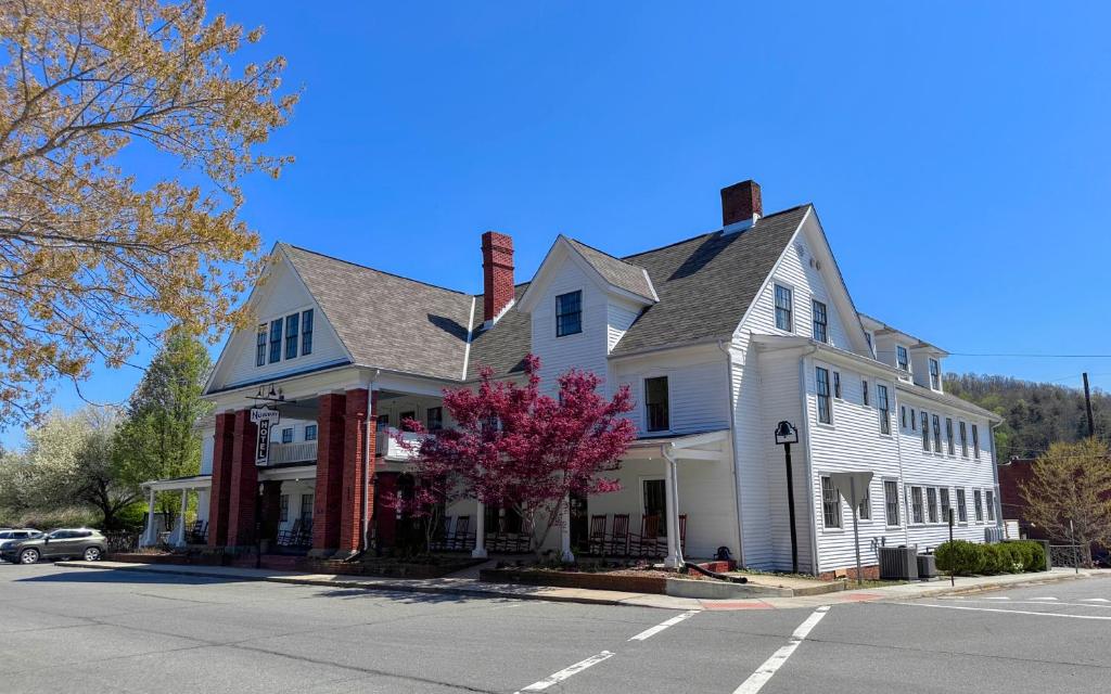 a white house with red chimneys on a street at The NuWray Hotel & Carriage House in Burnsville