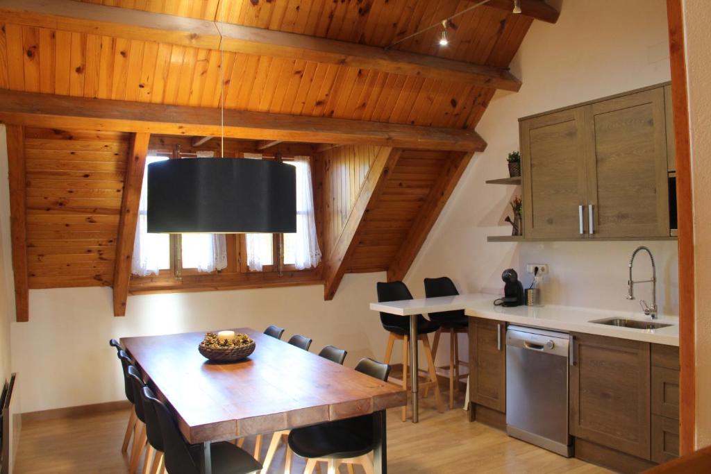 cocina con techos de madera, mesa y sillas en Casa Dula, en Pla de l'Ermita
